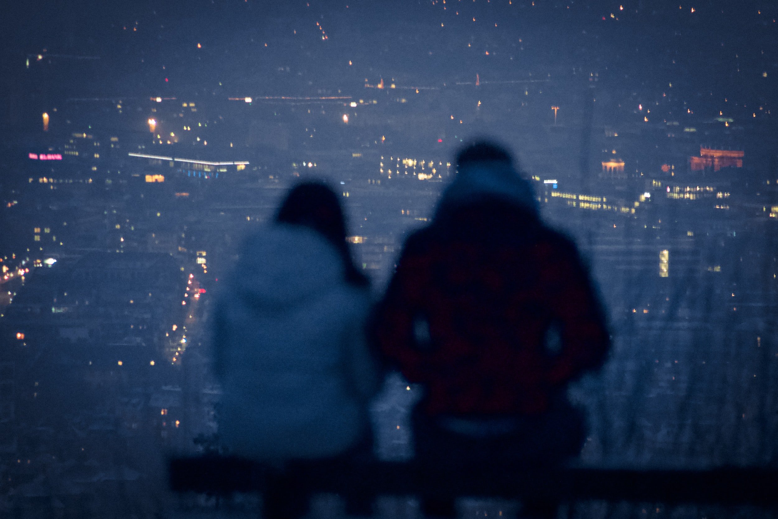 man and woman sit together and look out at the city lights at night