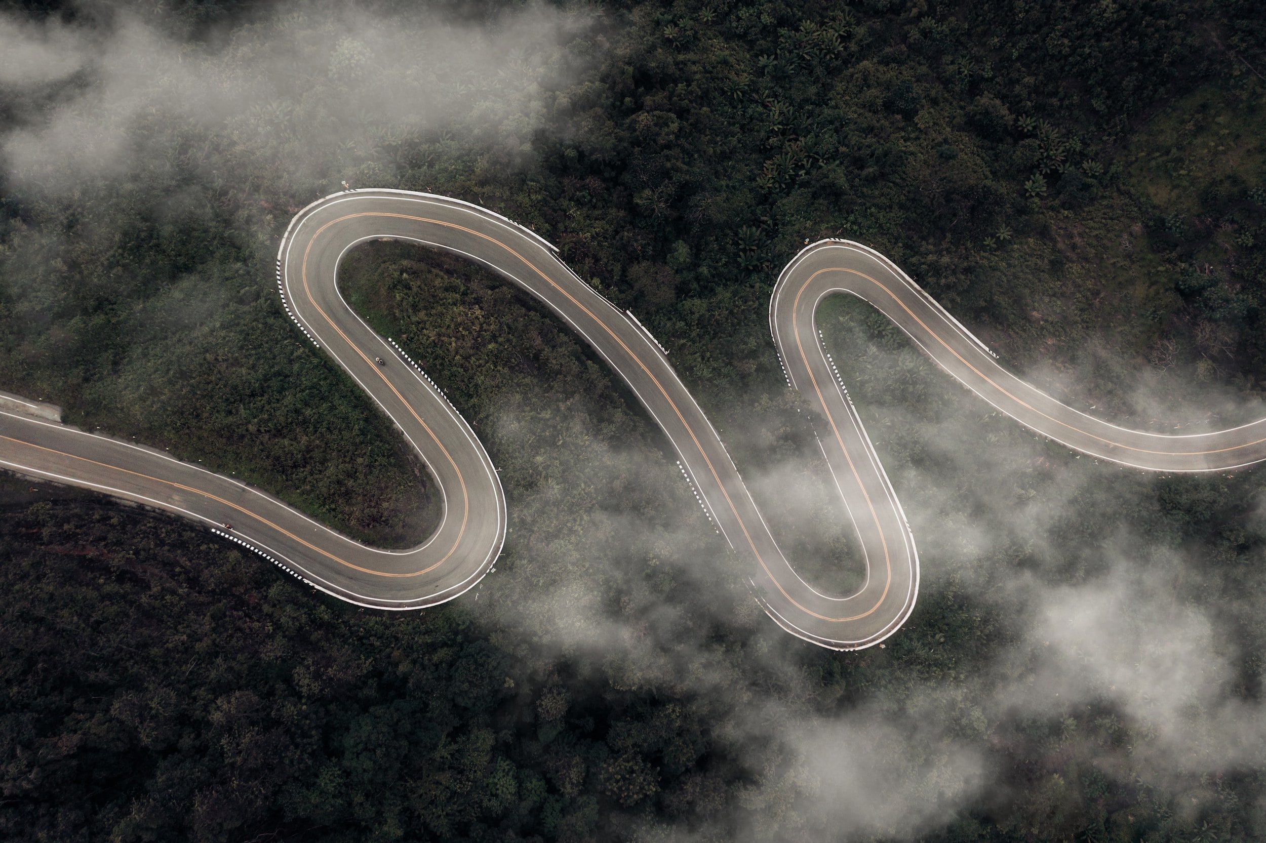 long curvy road through mountains and trees